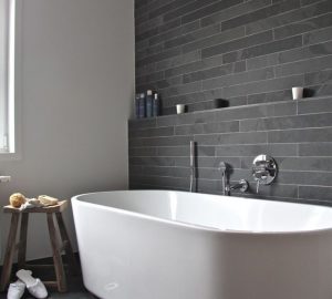 Transform Your Bathroom Into A Luxury Space In 5 Easy Steps - White Free Standing Bath, Grey Slated Walls & Wooden Stool.