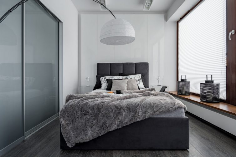 Gray and white bedroom with double bed, modern lamp and sliding door wardrobe