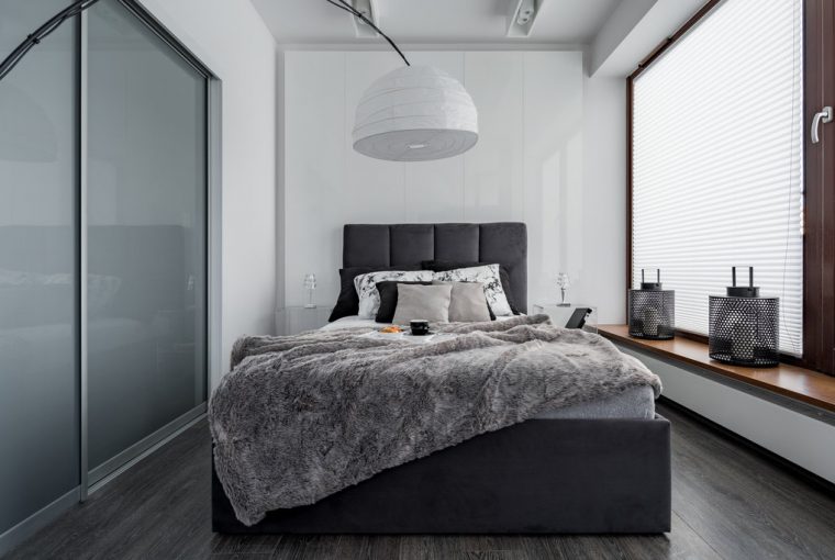 Gray and white bedroom with double bed, modern lamp and sliding door wardrobe