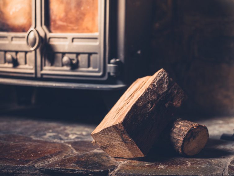 A small pile of logs by a wood burner