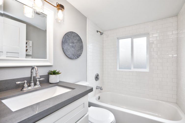 Modern bathroom interior with white vanity topped with grey countertop.