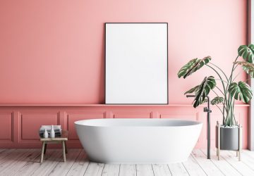 Interior of minimalistic bathroom with pink walls, wooden floor, white bathtub with vertical poster hanging above it and potted plant. 3d rendering mock up