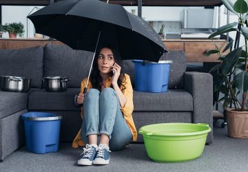 Women sat in loung with umbrella as ceiling leaking water