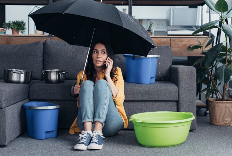 Women sat in loung with umbrella as ceiling leaking water
