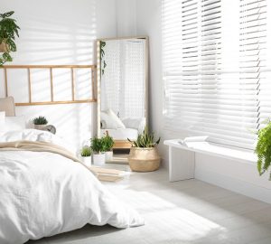 White decorated bedroom with large mirror and white wooden blinds