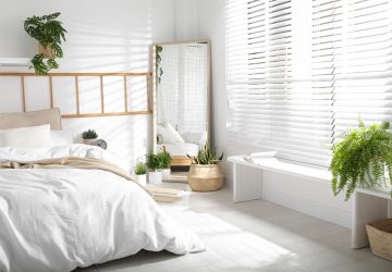 White decorated bedroom with large mirror and white wooden blinds