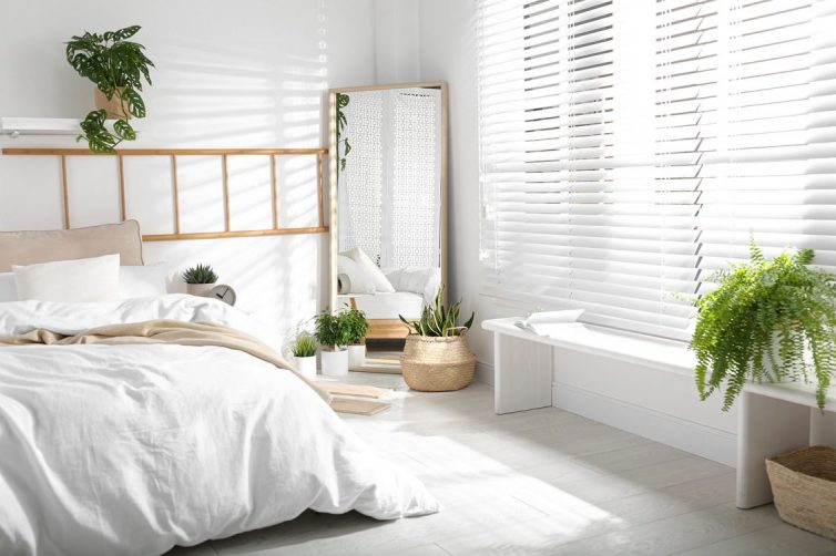 White decorated bedroom with large mirror and white wooden blinds