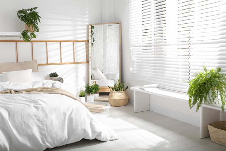 White decorated bedroom with large mirror and white wooden blinds