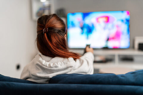 Women sat on blue sofa watching TV