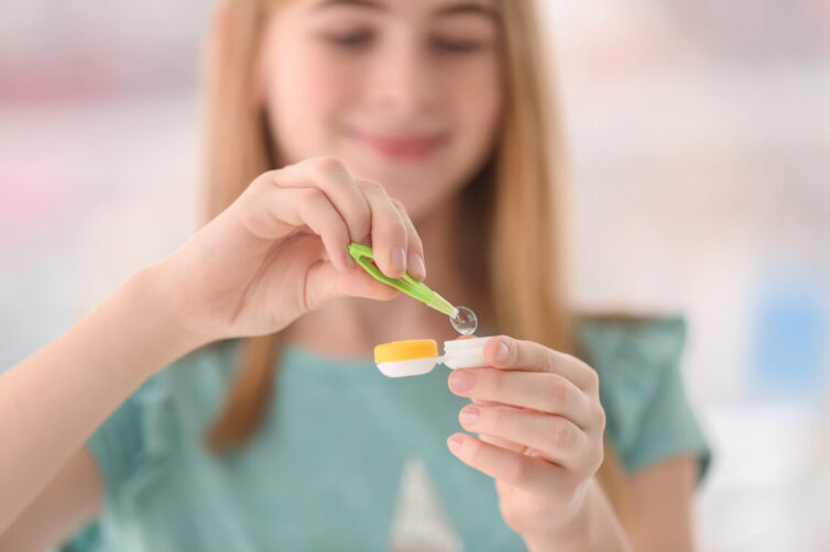 Young women placing contact lense into contact lense container