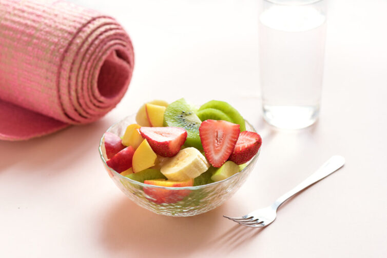 Bowl of fruit, yoga mat and glass of water