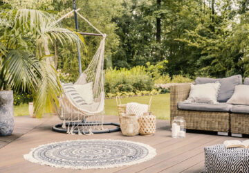 Hammock on patio with round rug and rattan sofa in the garden