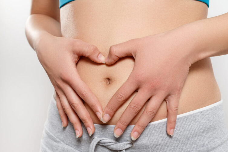 Woman shows two hands gesture heart on his stomach.