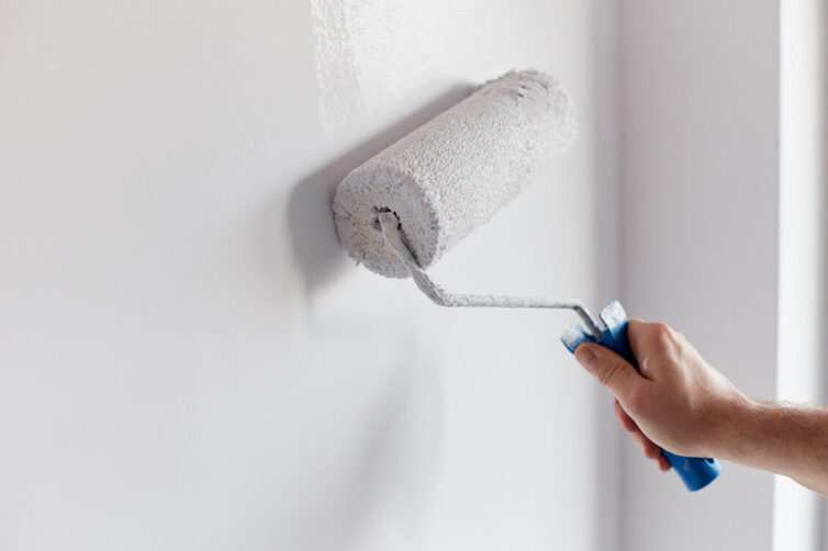 Painting wall with white paint on roller