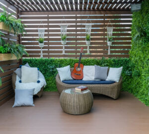 Fenced in garden with decking, plants and wicker furniture