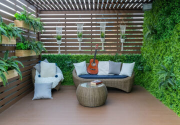 Fenced in garden with decking, plants and wicker furniture