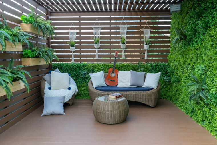 Fenced in garden with decking, plants and wicker furniture