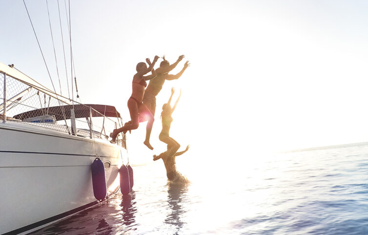 Friends jumping from sailboat on sea ocean trip