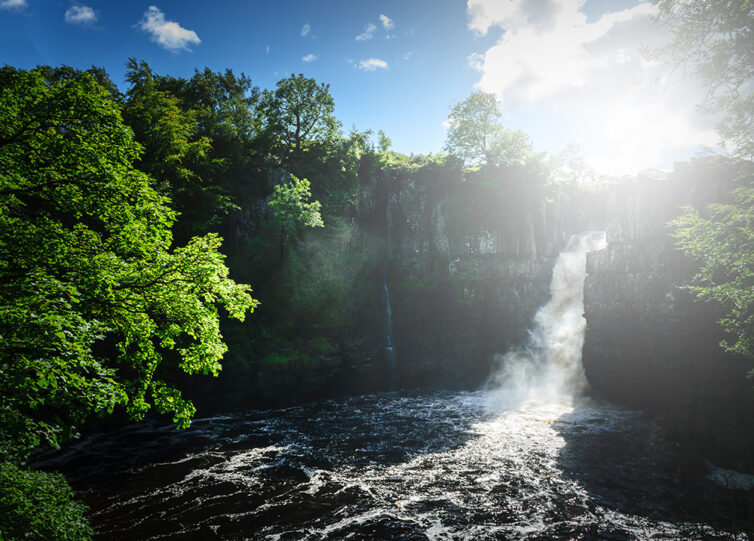 High Force Waterfall views from the south bank of the River Tees on the Pennine Way in woodland, UK.