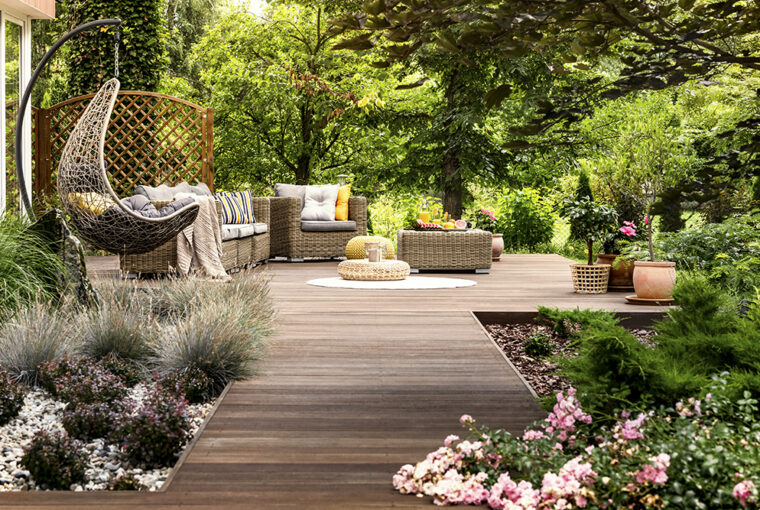 Wooden decking with wicker garden furniture. Surrounded by trees