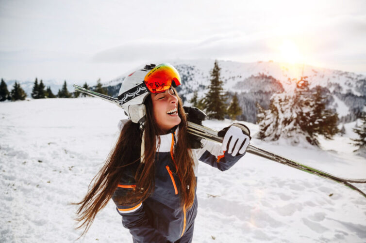 Woman carrying skis. Wearing ski googles.