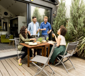 Garden party with two men and two women. Table and chairs and decking.