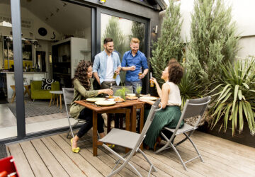 Garden party with two men and two women. Table and chairs and decking.