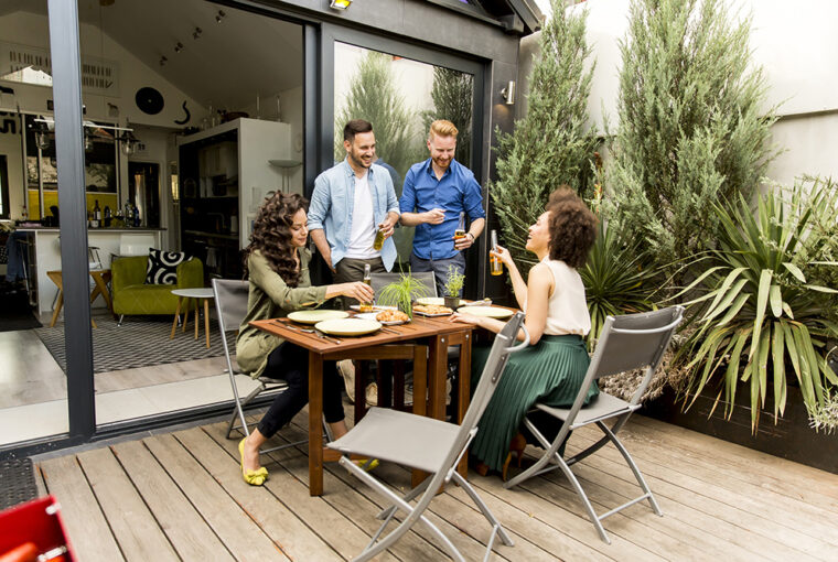 Garden party with two men and two women. Table and chairs and decking.