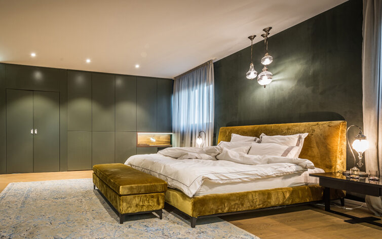 Green paintedd bedroom with gold bed. Large green built in wardrobes