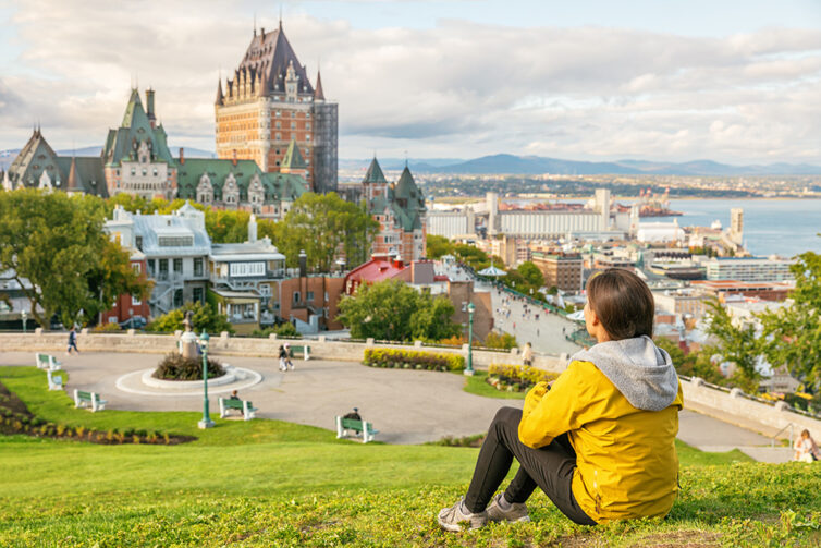 Femal student in Quebec city enjoying view of Chateau Frontenac castle and St. Lawrence river Canada