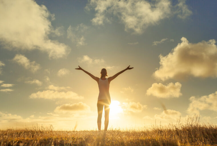 Women with arms in air embracing beautiful scenery and looking at the sky