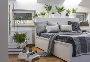 White bed and bedroom with house plants and grey bedding