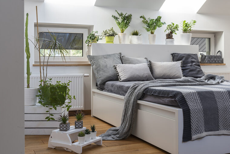 White bed and bedroom with house plants and grey bedding