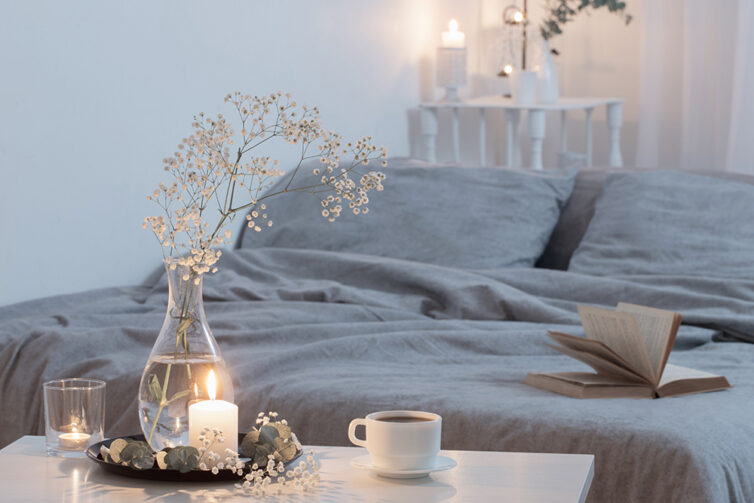 Peacefull bedroom with grey bedding, candle light and vase of flowers