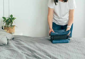 Woman folding clothes/ jeans in clutter free bedroom