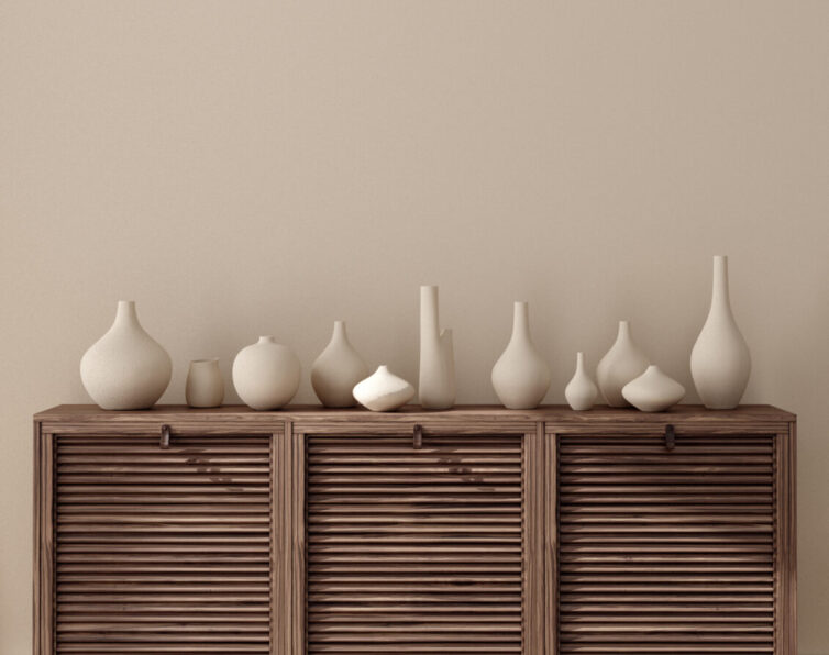 Light brown painted walls with brown wooden furniture covered in cream vases