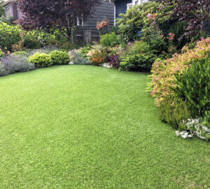 artificial lawn in the front yard with nice flowers and shrubs surrounding it