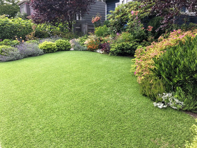 artificial lawn in the front yard with nice flowers and shrubs surrounding it