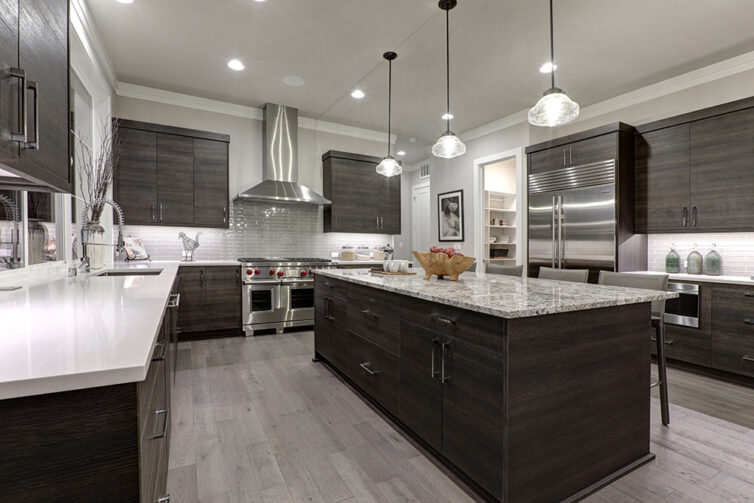 Grey laminate flooring with dark kitchen cupboards and white quartz countertops