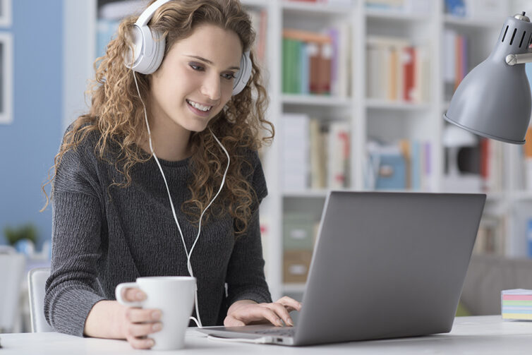 Women wearing headphones while using laptop