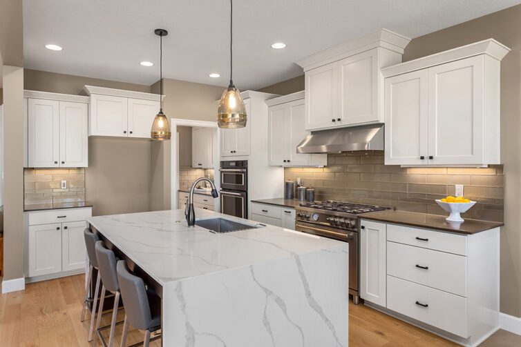 White kitchen cupboards with quartz counter tops and laminate flooring