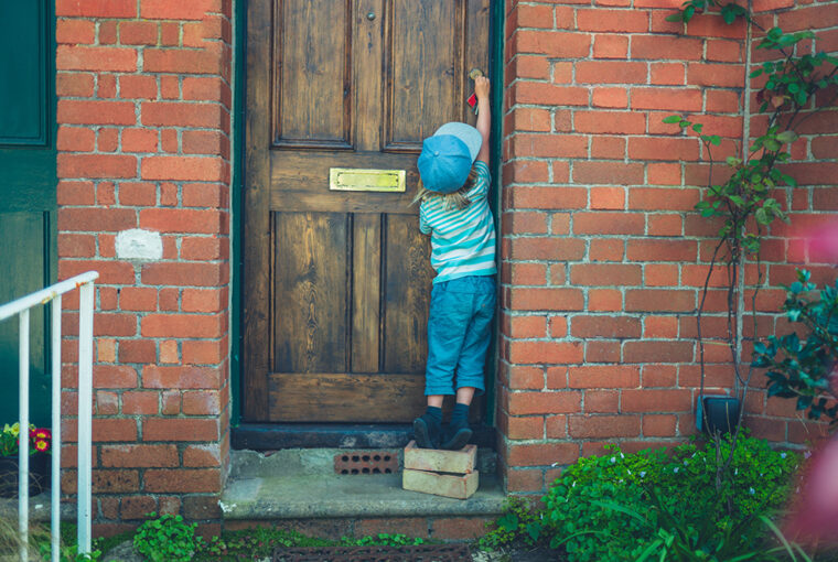 Child standing on bricks to unlock front door