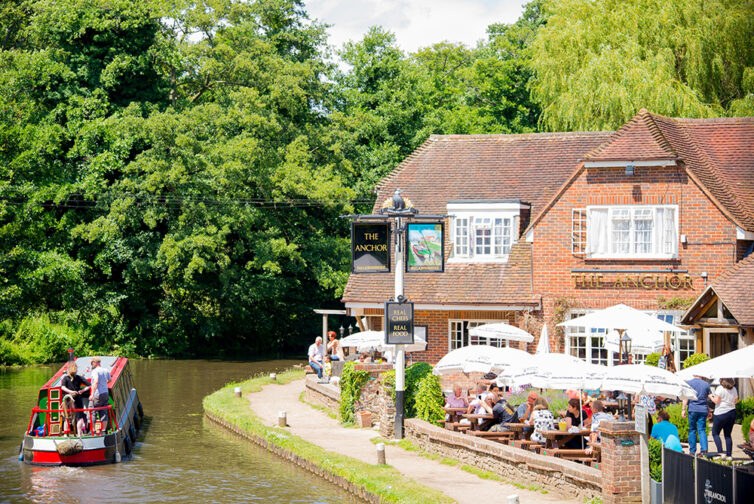 Narrow boat passes English pub on canal