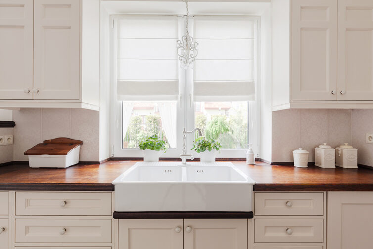 Large double white porcelain kitchen sink. Dark wood kitchen worktops and cream kitchen cupboards