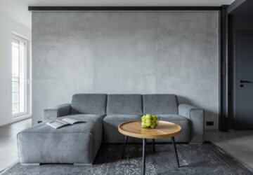 Concrete wall in living room, grey sofa and grey rug