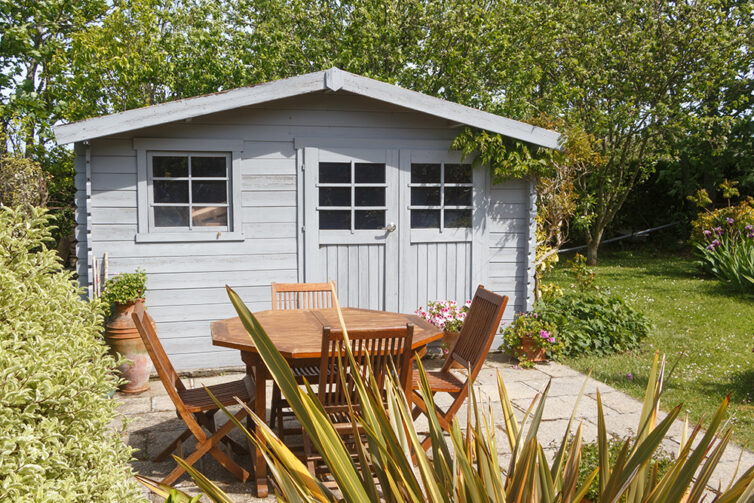 Grey wooden garden shed and wooden garden table and chairs