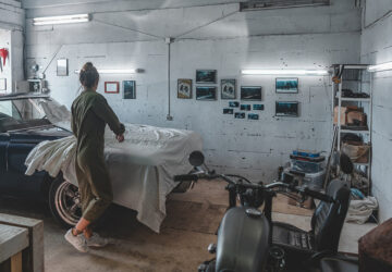 Women removing cover from vintage car in garage