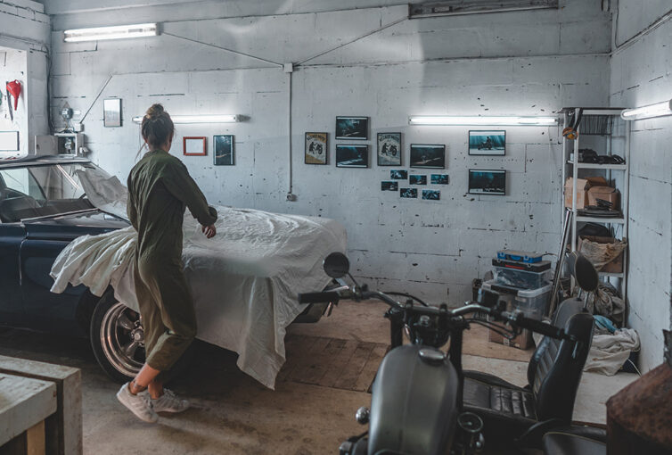 Women removing cover from vintage car in garage