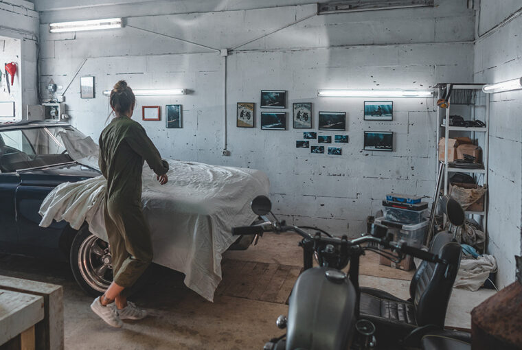 Women removing cover from vintage car in garage