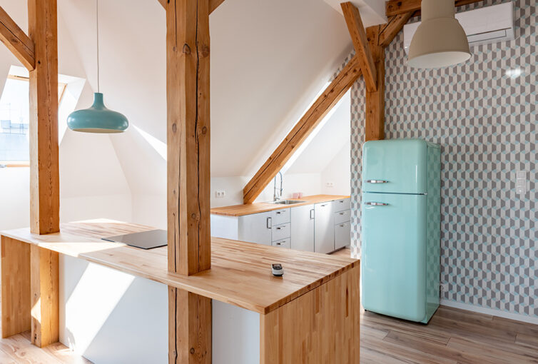 Small mint green fridge freezer in a retro style. Placed in loft apartment